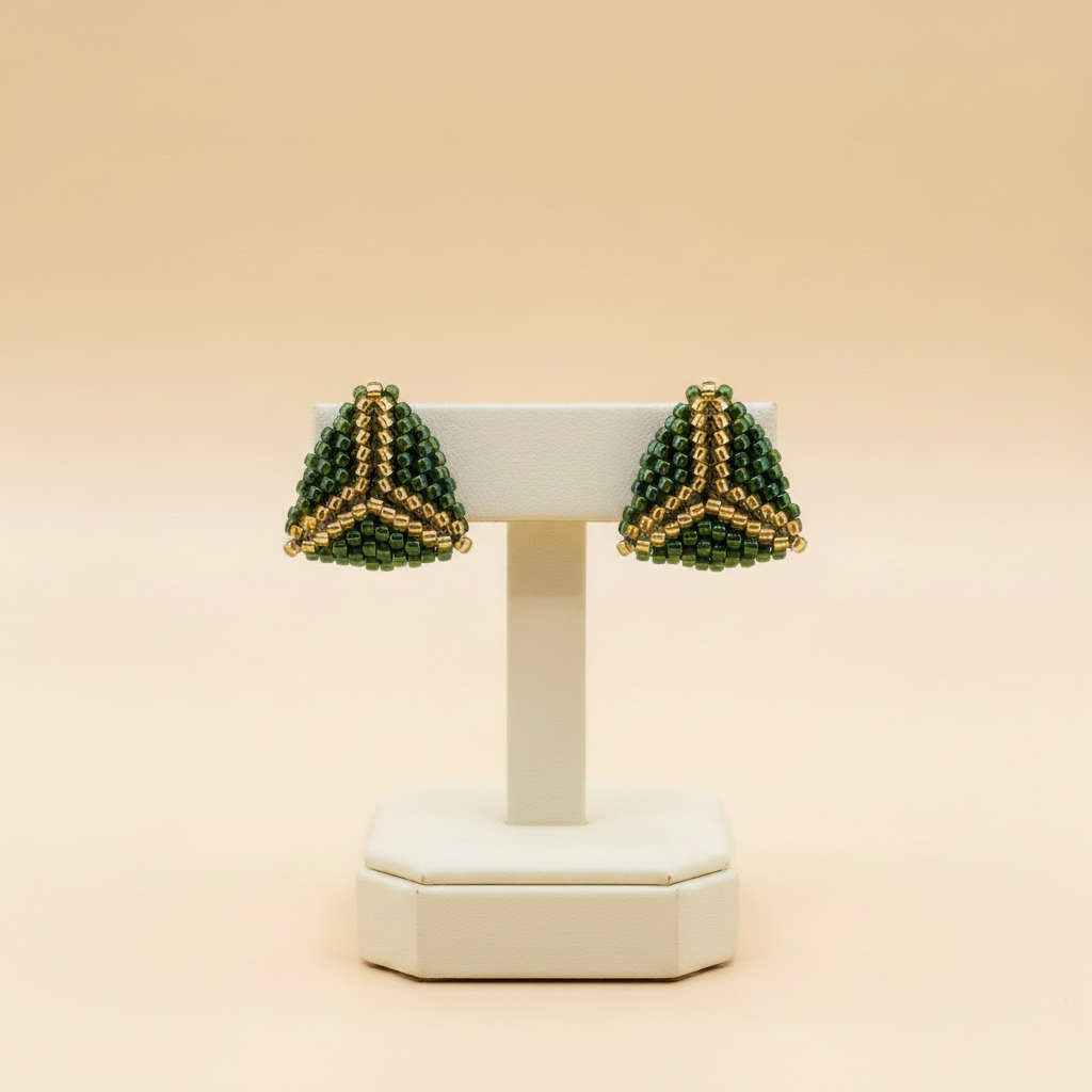 Matching deep-green and gold earrings on an ivory stand